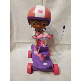   Doc McStuffins (Dr. Plüssi) baba rollerrel – használt, jó állapotban (23 cm) (d2)